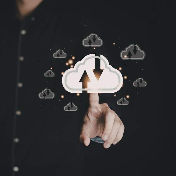 Una mano toque un icono central de nube prominente con flechas de carga y descarga, rodeado de iconos de nube más pequeños, que simboliza la escalabilidad proyectada y la gestión centralizada cloud para redes inalámbricas para empresas instaladas por Redlink en Jalisco.
