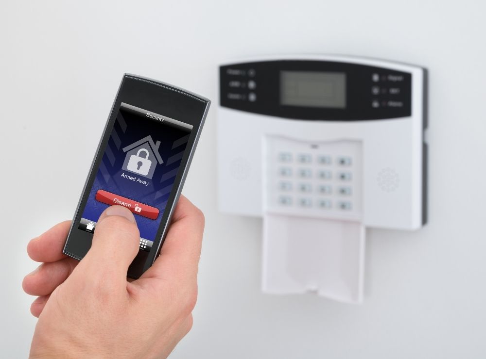Se muestra una persona que activa o desactiva su sistema de alarma de intrusión desde un dispositivo móvil.
